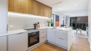 A modern kitchen with white cabinetry, a wooden upper wall, and a built-in oven.