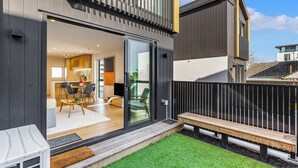 A modern house with a large sliding glass door leading to a dining area with a table and chairs.
