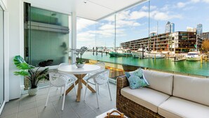 Un balcon donnant sur un port de plaisance, un canapé blanc et une table à manger avec des chaises.