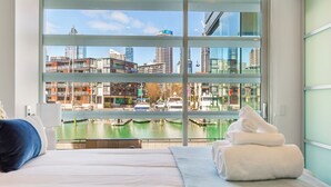 Une chambre d’hôtel dotée d’une grande fenêtre donnant sur un paysage urbain et sur une étendue d’eau.