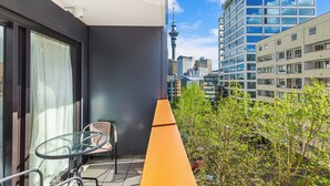 A balcony with a glass table and chair, a view of the city skyline, and a building with a distinctive tower. - Sleek central stay with balcony by Zodiak Stays (Auckland)