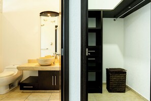 A modern bathroom with a beige sink, a white toilet, and a dark wooden cabinet.