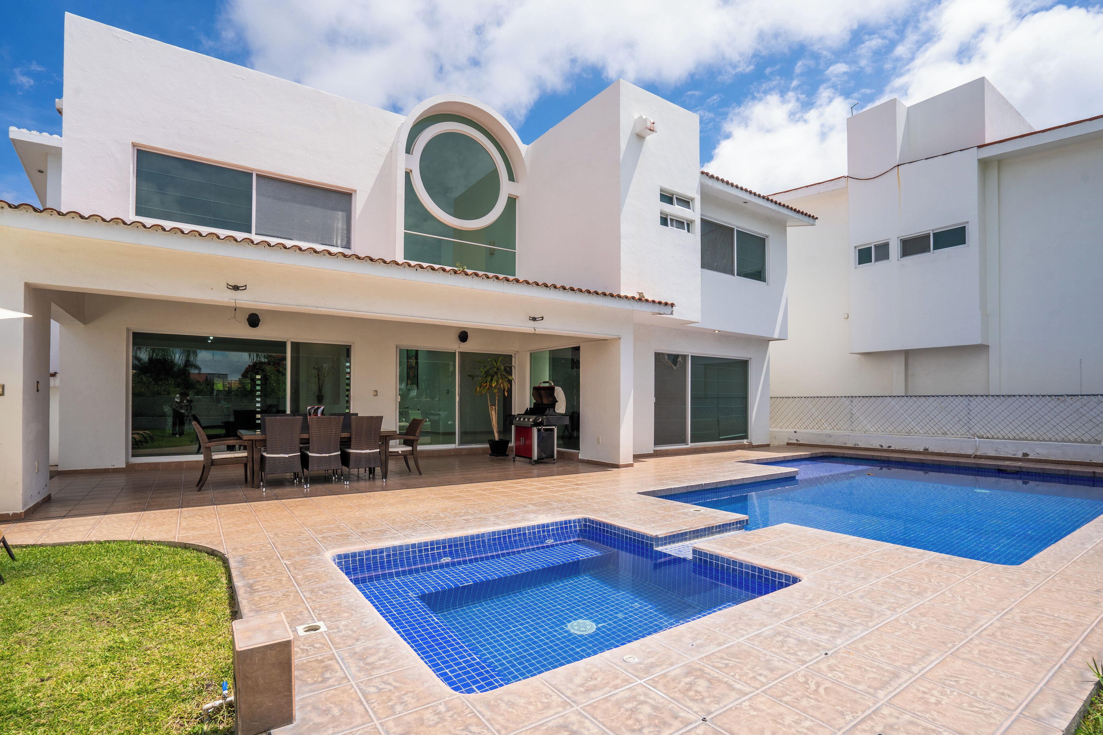 A modern house with a swimming pool, outdoor seating, and a covered patio.