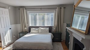 A bedroom with a bed, nightstands, a dresser, a fireplace, and a large mirror. - Charming renovated 1-bedroom in downtown Biddeford (Biddeford)