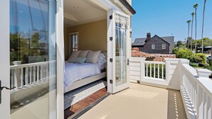Ein Schlafzimmer mit Bett, einer Schiebetür und einem Balkon mit weißer Brüstung.
