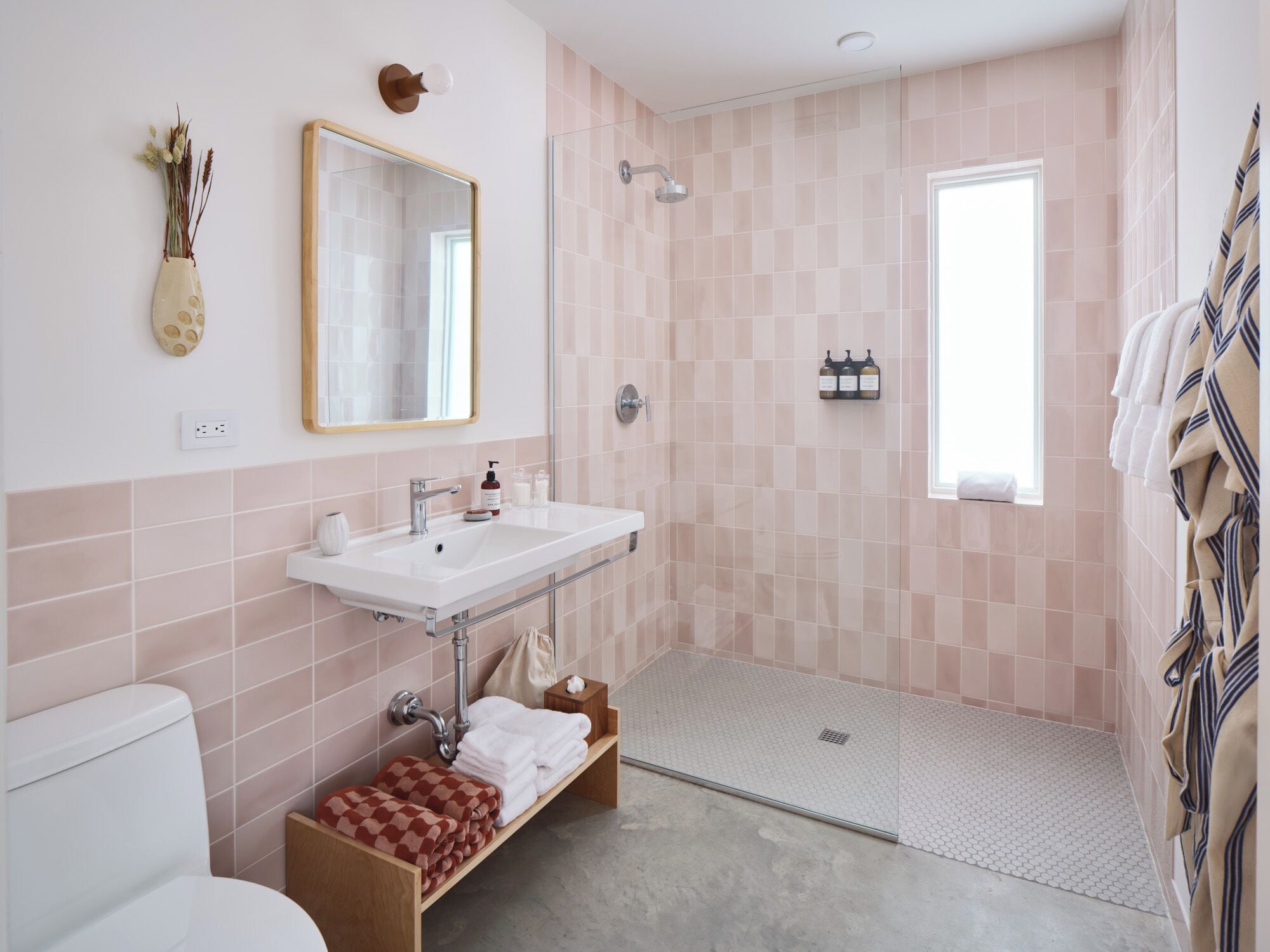 Un baño moderno con un lavamanos blanco, cabina de ducha con mampara de cristal y un inodoro.