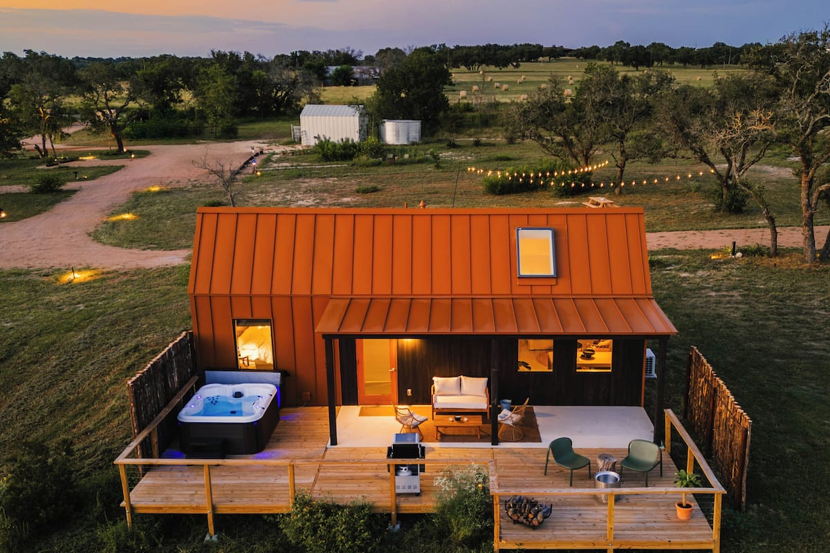 Eine rustikale Holzhütte mit Whirlpool, Sitzgelegenheit im Freien und einer Terrasse.