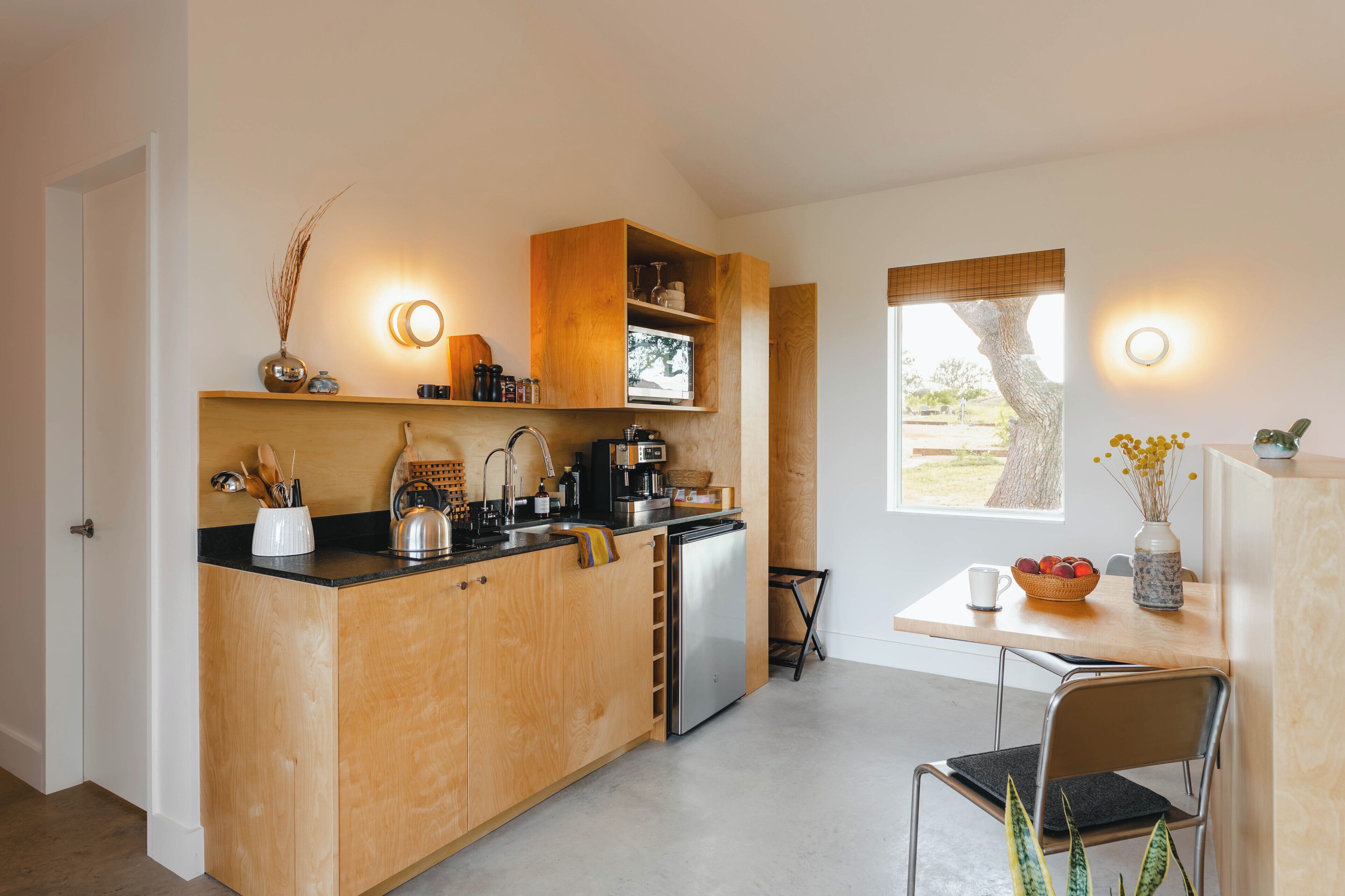 Una cocina compacta con armarios de madera, horno integrado y comedor con mesa y sillas.