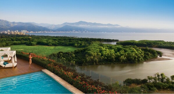 A poolside area with a view of a city skyline and mountains in the distance.