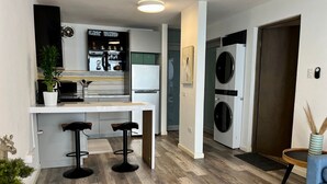 Eine moderne Küche mit einer zentralen Kochinsel, Barhocker und einer integrierten Waschmaschine.