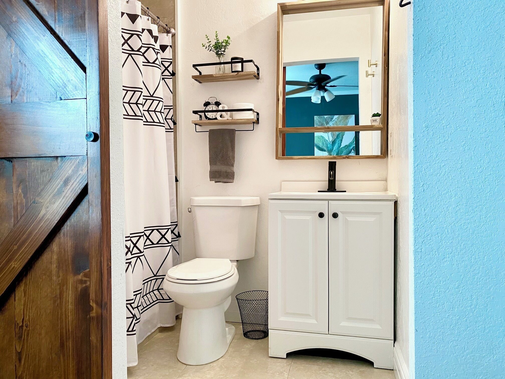 A bathroom with a white toilet, a white cabinet, a mirror, and a ceiling fan.
