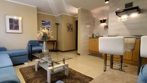 Un salon moderne avec un canapé bleu, une table basse en verre et un vase de fleurs.