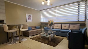 Un salon moderne comprenant un canapé, une table basse, un téléviseur et un coin repas avec une chaise et une table.