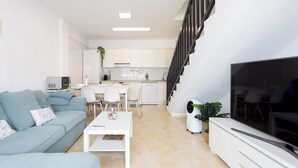 A modern living room with a sofa, coffee table, TV, and a staircase leading to an upper level. - Home2Book Design Duplex Puertito de Güímar, Pool (Puertito de Güímar)