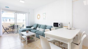 A modern living room with a sofa, a dining table, and a TV. - Home2Book Design Duplex Puertito de Güímar, Pool (Puertito de Güímar)