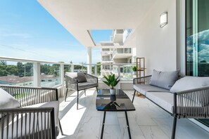A balcony with a sofa, chairs, and a table, overlooking a cityscape. - King Beds, Rooftop, Balcony, Gym, Pool (Hollywood)