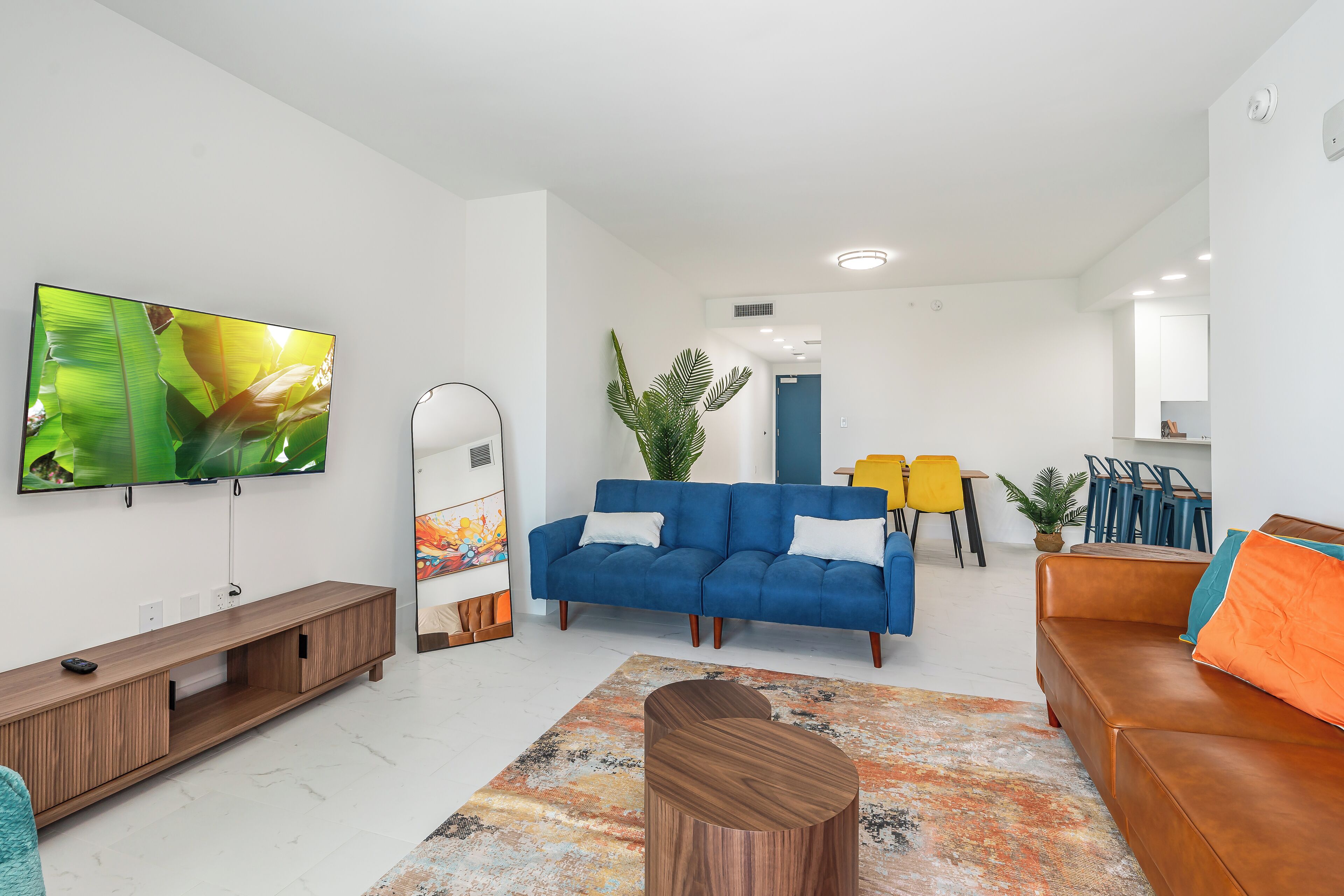 A modern living room with a blue sofa, a wooden coffee table, and a large flat-screen TV.