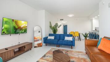A modern living room with a blue sofa, a wooden coffee table, and a large flat-screen TV.