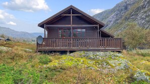 A wooden cabin with a balcony, set in a mountainous area with rocky terrain and sparse vegetation. - Gorgeous home in Dirdal (Dirdal)