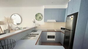 A compact kitchen with a built-in oven, a microwave, and a refrigerator.