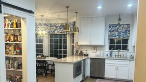 A kitchen with white cabinets, a central island, a dining area with a table and chairs, and a patterned rug. - Welcome to the perfect Oxford getaway for an Ole Miss game.  (Oxford)