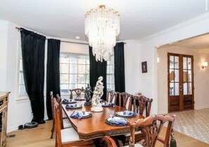 A dining room with a chandelier, wooden table, chairs, and a statue centerpiece.