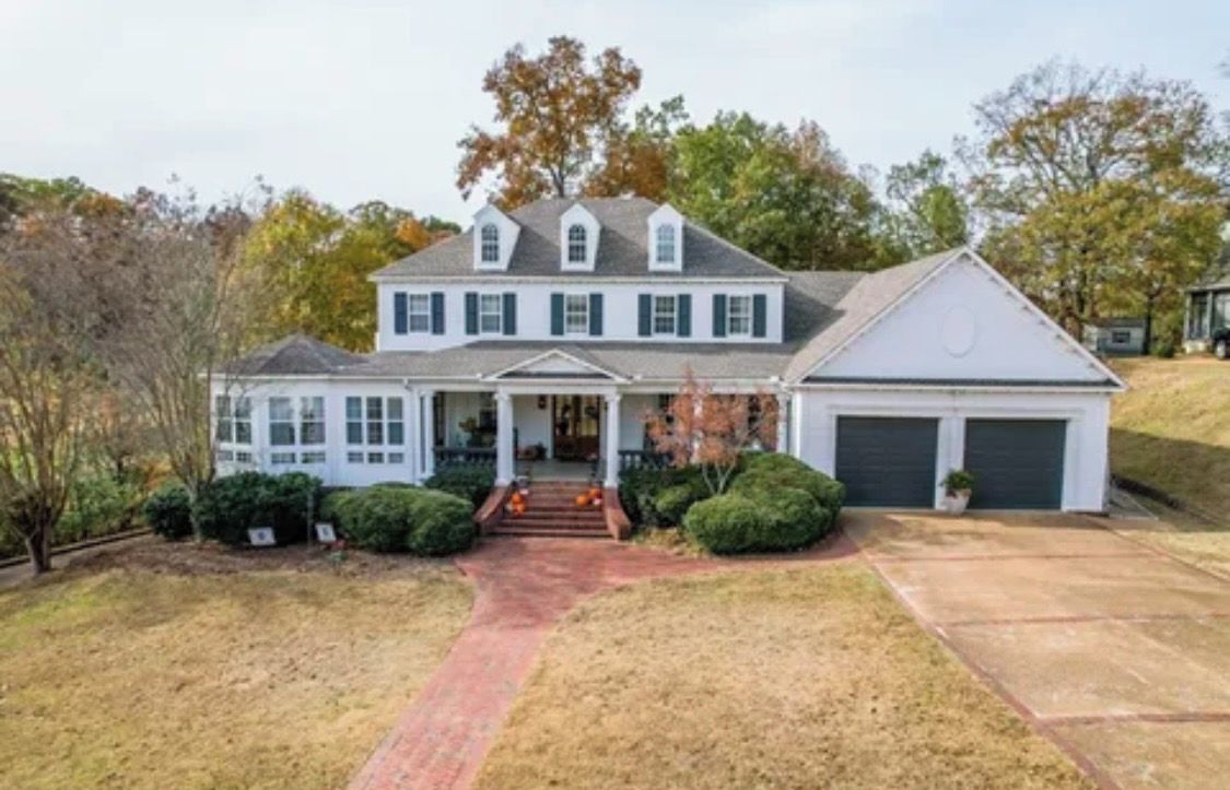 A two-story house with a front porch, a garage, and a well-maintained lawn.