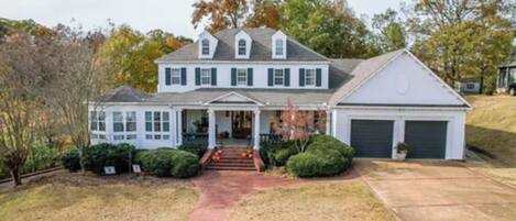 A two-story house with a front porch, a garage, and a well-maintained lawn.