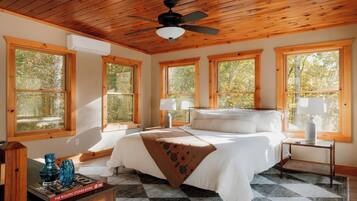 A bedroom with a bed, two bedside tables, a ceiling fan, and large windows.