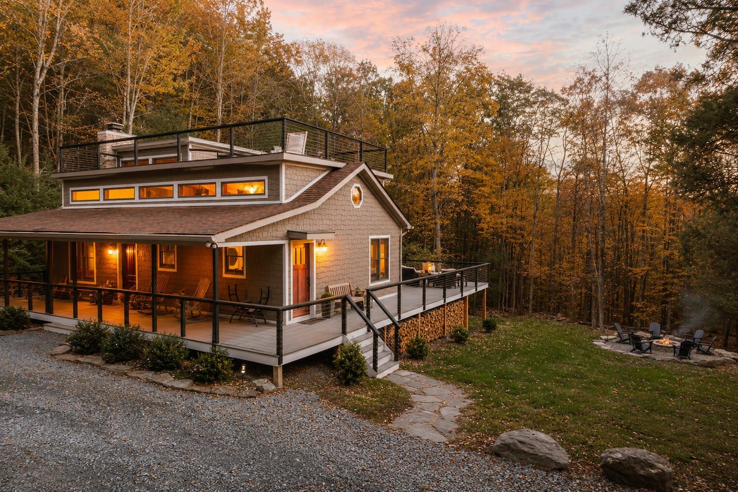 A modern two-story house with a deck, surrounded by a forest.