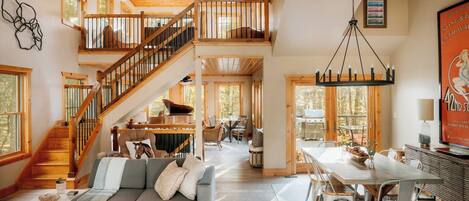 A spacious living area with a staircase, a dining table, and a fireplace.