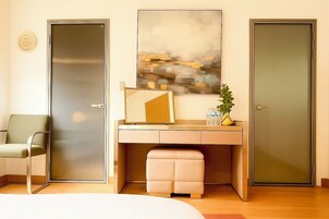 Una habitación de hotel moderna con una cama, un escritorio con silla, un cuadro abstracto grande y dos puertas.