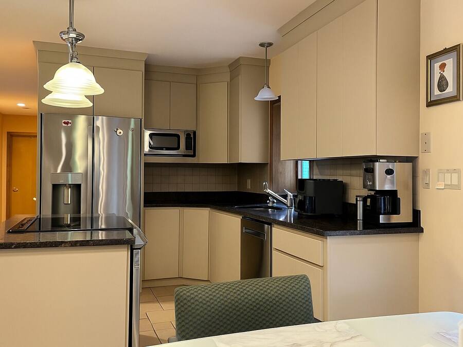 Cocina compacta con refrigerador, microondas, cafetera y un lavamanos pequeño.