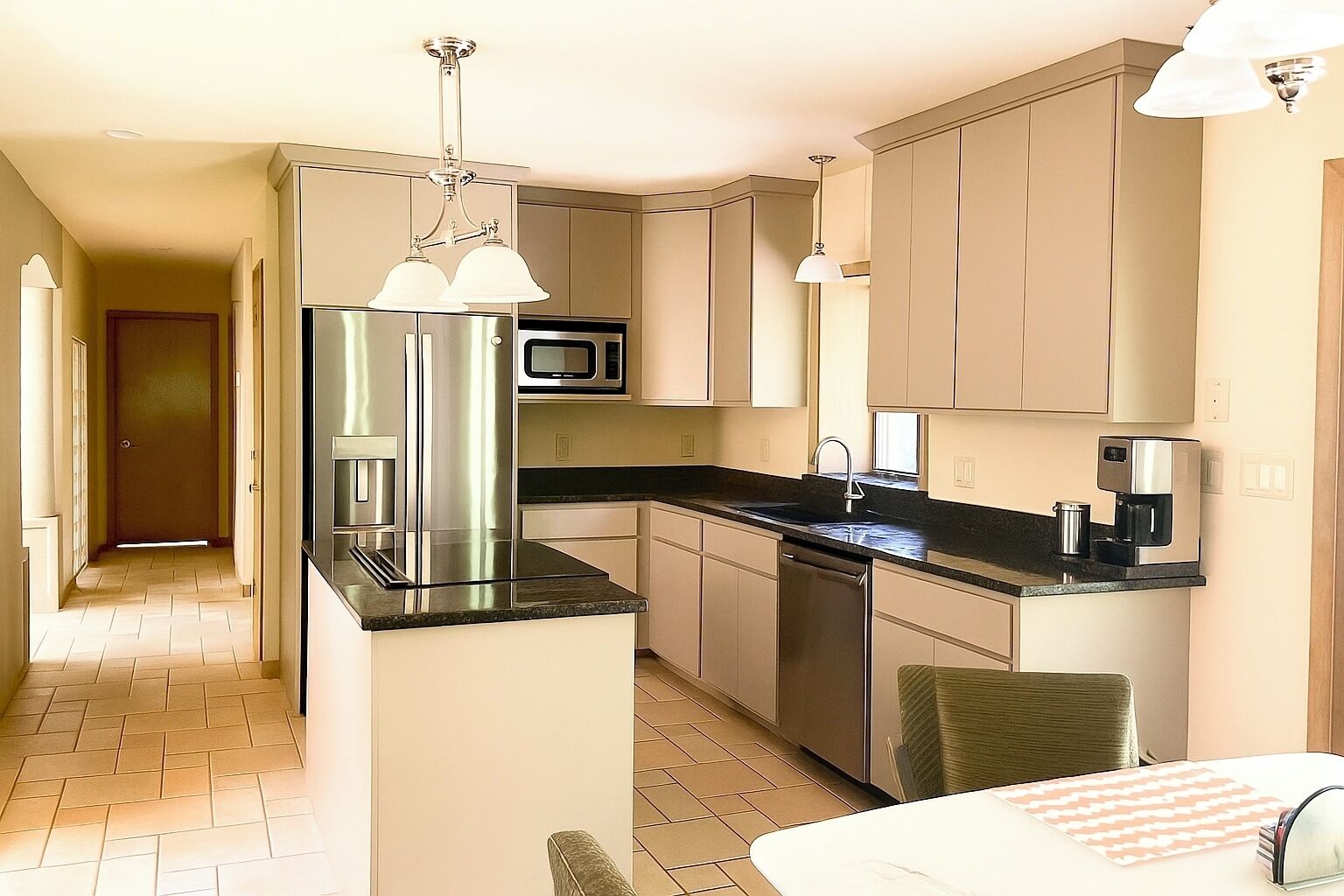 A modern kitchen with stainless steel appliances, a black countertop, and light-colored cabinetry.