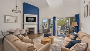 A spacious living room with a fireplace, a dining area, and a balcony with outdoor furniture.