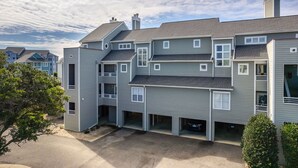 A multi-story residential building with a central courtyard, multiple balconies, and a garage.