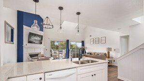 A modern kitchen with a large island, white cabinetry, and pendant lighting.