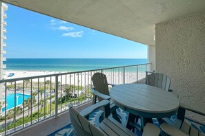A balcony with a view of the beach and pool, featuring a round table and Adirondack chairs. - BEACHFRONT, TWO POOLS, PRIVATE BALCONY! (Orange Beach)