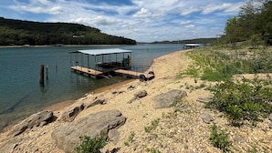 Un muelle junto al lago con un área de descanso cubierta y un bote pequeño.