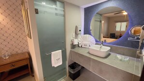 Une salle de bain moderne avec une douche à parois de verre, un lavabo blanc et un miroir agrémenté d’une touche de bleu.