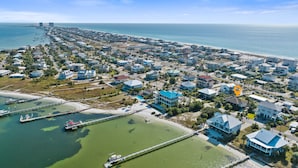 Vista aérea de uma área residencial costeira com casas, um cais e uma praia.