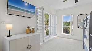 Quarto com vista para a praia, persianas brancas, ventoinha de teto e beliche.