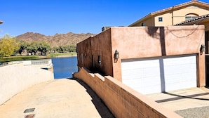 Una propiedad residencial con garaje, un camino de hormigón y vistas a un río y montañas.