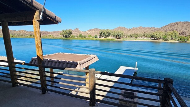 Un muelle de madera con vistas a un lago tranquilo, con montañas al fondo.