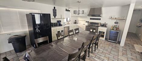 A modern kitchen with a large island, stainless steel appliances, and a dining area with a table and chairs.