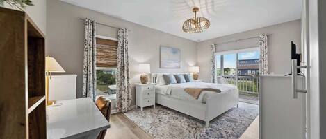 A bedroom with a bed, bedside tables, a desk, and a view of the outside.