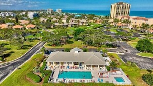 A resort with a large pool, multiple guest rooms, and a view of the ocean.