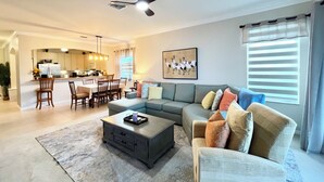 A modern living room with a sofa, coffee table, and dining area.