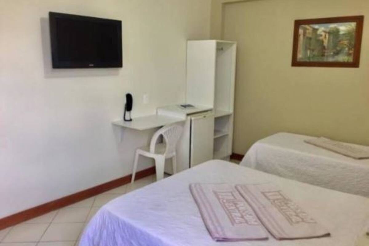 A hotel room with a bed, a desk with a chair, a television mounted on the wall, and a painting on the wall.