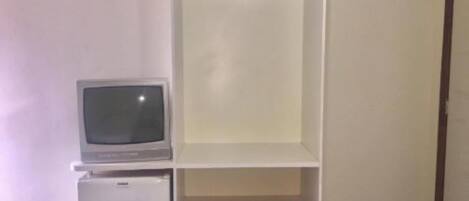 A room with a white wardrobe, a small white refrigerator, and a television on top of the refrigerator.